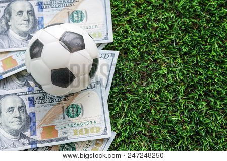Football Business Concept : A Fooball On Dollar Bills And Green Grass Background. Soccer Gambling Mo