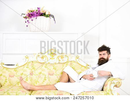 Luxury Life Concept. Man Sleepy In Bathrobe Drinks Coffee In Luxury Hotel In Morning, White Backgrou