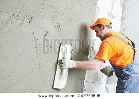 Renovation at home. Plasterer spreading plaster on wall.