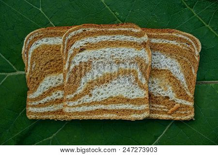 Three Pieces Of Square Colored Bread On A Green Leaf