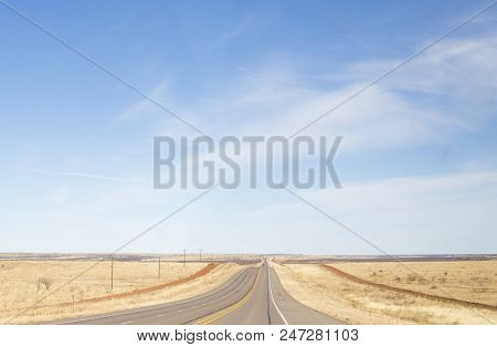 A Long Stretch Of Road In A Dry Climent With A Beautiful Blue Sky