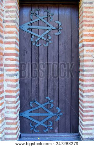 Ancient Wooden Door With Iron Forged Hinge. Old Church Door Leading To Religious Place Made From Red