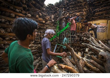 VARANASI, INDIA - MAR 22, 2018: Locals near Holy Ganges weighed for sale wood for cremation. Manikarnika Ghat is one of the ghats in Varanasi and is most known for being a place of Hindu cremation.