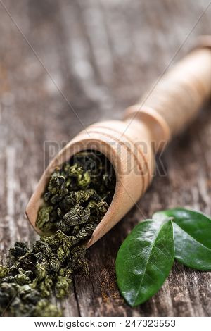 Spoon Of Dried Green Tea Leaves On Wooden Background. Leaves Of Green Tea Close Up