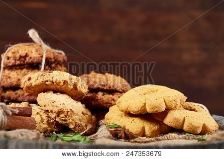 Conceptual Composition With Assortment Of Cookies, Cinnamon Sticks Bunch And Dried Oranges On A Wood