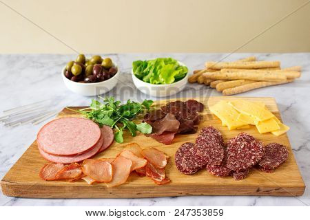 Appetizer Table For Wine Or Beer With Sausages, Dried Meat And Cheese, Served With Grissini, Herbs A