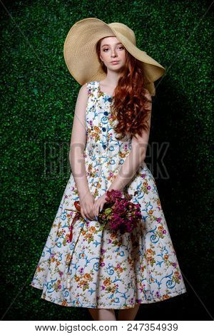 Portrait of a cute girl teenager wearing summer dress and hat over lawny background. Beauty, fashion.