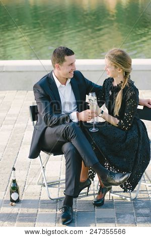 Young Couple Driving Champagne On A River Bank