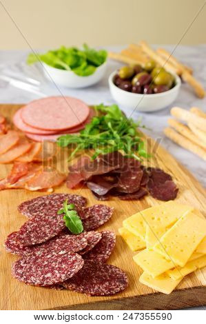 Appetizer Table For Wine Or Beer With Sausages, Dried Meat And Cheese, Served With Grissini, Herbs A