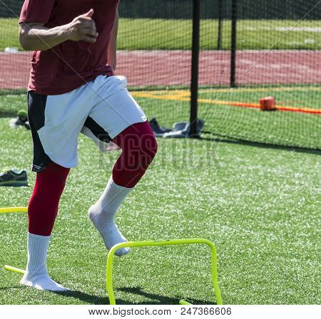 A High School Track Aand Field Sprinter Is Running Over Yellow Mini Hurdles In His Socks After Takin