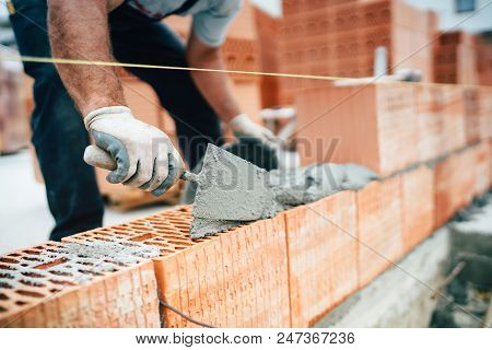 Professional Worker Using Pan Knife For Building Brick Walls With Cement And Mortar