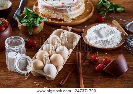 Strawberry Tart Covered With Whipped Sour Cream Surrounded By Organic Ingredients Over Wooden Backgr