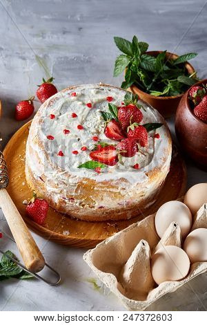 Strawberry Tart Covered With Whipped Sour Cream Surrounded By Organic Ingredients Over White Backgro