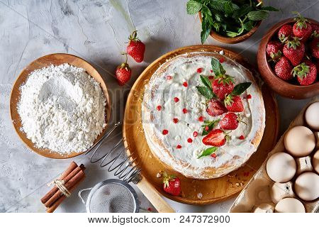 Strawberry Tart Covered With Whipped Sour Cream Surrounded By Organic Ingredients Over White Backgro