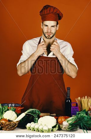 Chef With Sexy Face Poses In Uniform On Red Background. Cuisine And Professional Cooking Concept. Ma