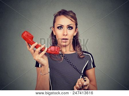 Young Woman Looking At Camera With Bewilderment Holding Old-fashioned Red Handset.