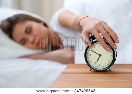 Sleepy Young Woman Stretching Hand To Ringing Alarm Willing Turn It Off. Early Wake Up, Not Getting 