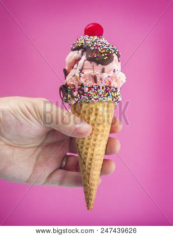 Hand Holding An Ice Cream Cone With A Cherry On Top