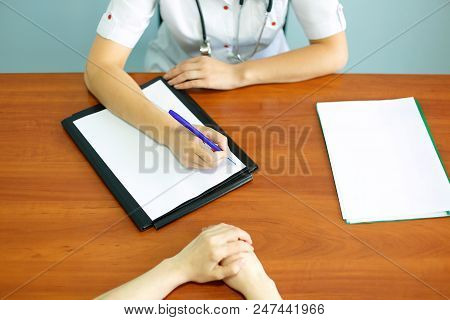 Close Up Of Patient And Doctor Taking Notes