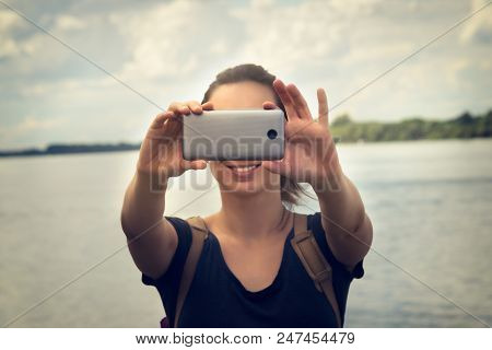 Selfie photo in vacation. Young girl taking selfie with mobile phone in vacation. Selfie in vacation. Tourist taking selfie photo. Girl capturing selfie photo in vacation. Selfie picture. Vacation. travel