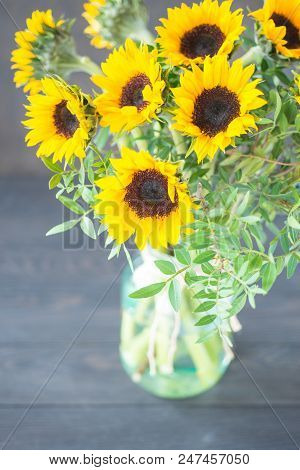 Bouquet Of Bright Sunflowers In A Glass Jar On A Wooden Table.