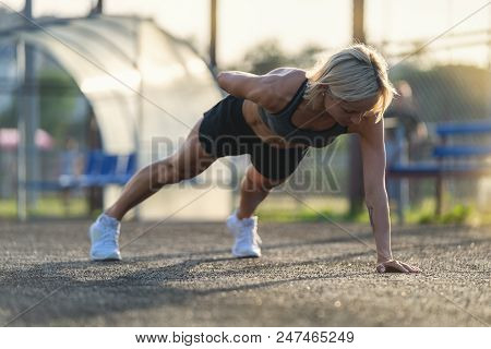 Young Attractive Blonde Woman Doing Push Ups Outdoors At Sunsut Light