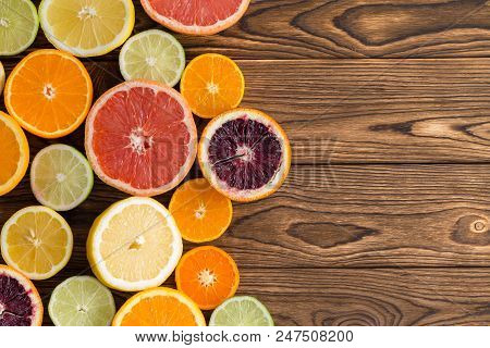 Array Of Fresh Juicy Halved Citrus Fruits Arranged To The Side On A Wooden Background With Copy Spac