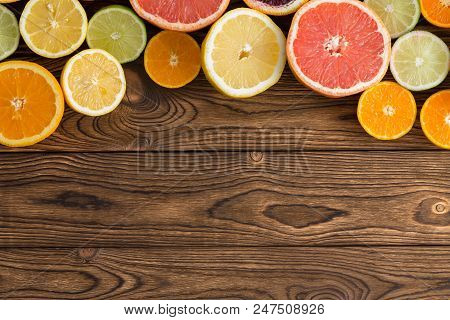 Curved Border Of A Variety Of Colorful Halved Succulent Fresh Tropical Citrus Fruit On A Rustic Wood