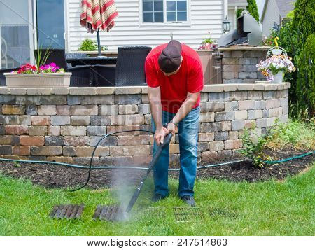 Man Pressure Cleaning Dirty Grill Plates From A Bbq Using A Hosepipe And Nozzle As He Stands On The 