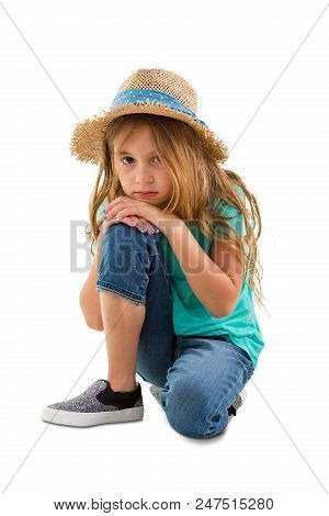 Depressed Solemn Little Girl Staring At The Camera As She Kneels Resting Her Chin On Her Knee Isolat
