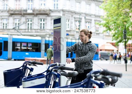 Young Boy Hiring Bicycle In City, Road Trafic And Pedestrians In Background. Concept Of Urban Lifest