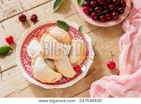 Pies With Cherries, Sprinkled With Powdered Sugar And Berries Of Fresh Cherries On A Wooden Surface.