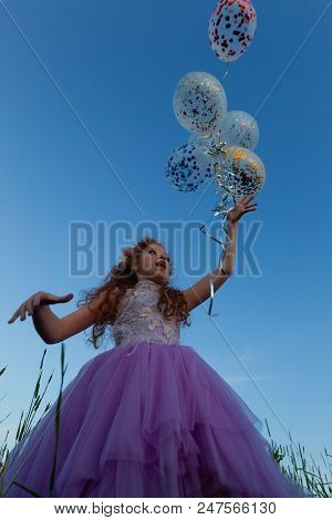Little Girl With Balloons On A Walk In The Field