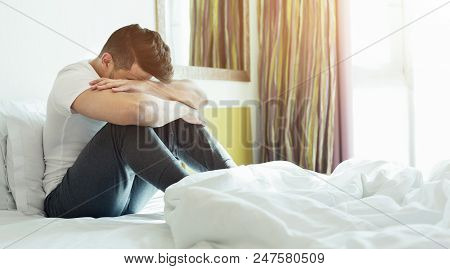 Depressed Or Tired Man Sitting On Bed In Hotel Room