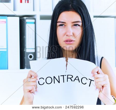 Young Angry Female Office Worker Ripping Contract At The Desk.