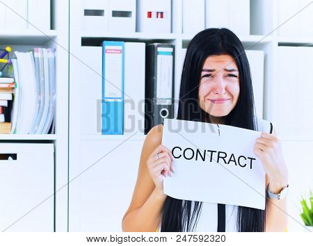 Young Unhappy Female Office Worker Ripping Contract At The Desk.
