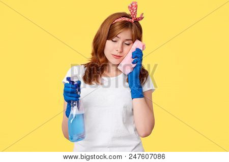 Sleepy Female Leans At Sponge, Being Tired After Tudying Up, Holds Bottle With Detergent, Wears Head