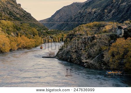 A Jet Boat On The Water In The Distance In A Winding Rocky Gorge In New Zealand