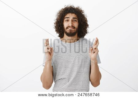 Portrait Of Worried Handsome Hispanic Guy With Afro Hairstyle In Striped T-shirt, Biting Lip Anxious