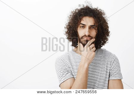 Smart Thougtful Attractive Hispanic Guy With Beard And Curly Hair, Holding Hand On Chin, Thinking An