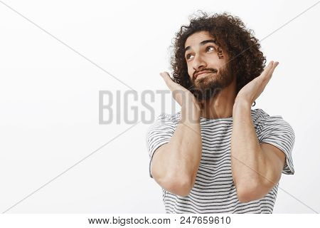 Indoor Shot Of Carefree Good-looking Bearded Guy With Afro Hairstyle, Looking Away And Smiling With 