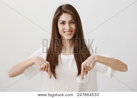 Trust Me And Look Down. Portrait Of Gorgeous Woman Wearing Casual Clothes Pointing Down With Both In