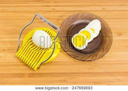 Egg Slicer With Peeled Egg In It And Sliced Boiled Egg On A Dark Glass Saucer On A Wooden Bamboo Sur