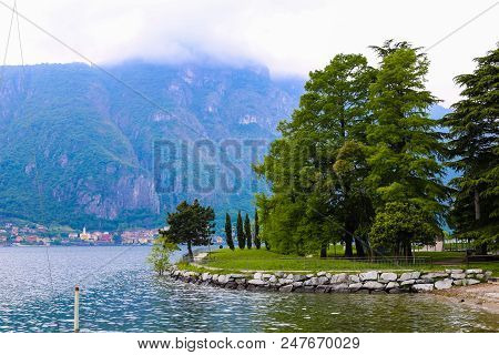 Green Trees Near Lake Como In Mandello Del Lario And Alps Mountain In Clouds. Concept Of Seascape An