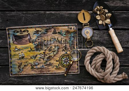 Treasure Map, Shovel Full Of Gold Ore, Compass, Rope And Magnifying Glass On Aged Wooden Table Backg
