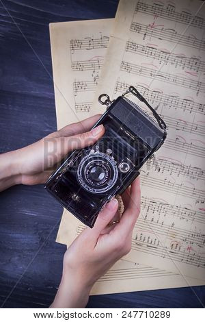 November 17, 2017. Krakow, Poland. Vintage Camera Zeiss Icon, Female Hands And Notes On A Dark Backg