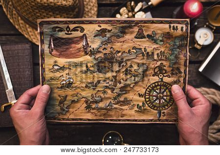 Treasure Map In Treasure Hunter Hands. Pirate Man Learning An Old Map With Red Mark.