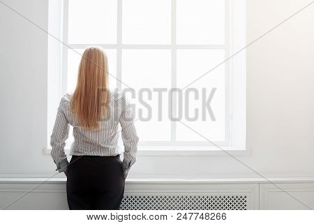 Back View Of Young Boss Dressed In Formal Clothes Standing At The Window In Office
