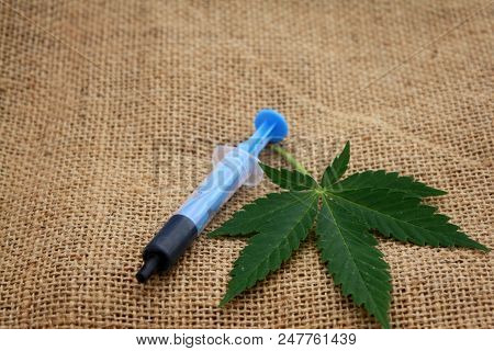 Hash Oil Phoenix Tears Medicine In Little Syringe With A Cannabis Marijuana Leaf On Linen Jute Surfa