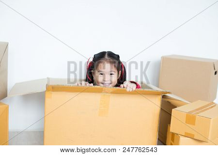 Asian Girl Playing In The Box At Home. Kid Sitting Inside Box With Attractive Smiling.